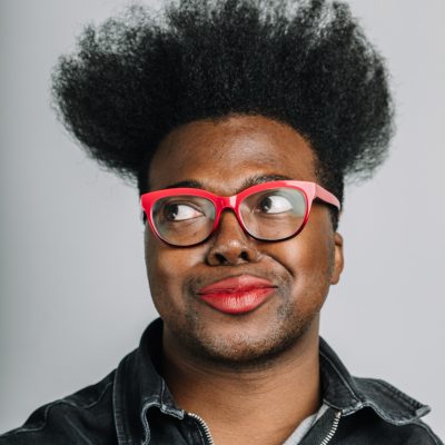 Tre'vell Anderson wearing red glasses and looking up and to the left