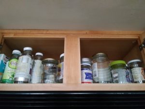 a kitchen cabinet full of empty glass jars and bottles