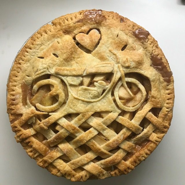 A pie with a bicycle and heart carved in the crust