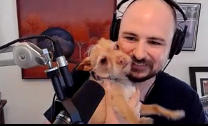 A man holding a small dog next to a microphone