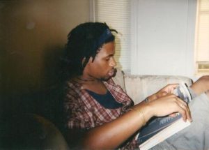 Mike Eagle as a teenager reading a book while he wears a plaid shirt