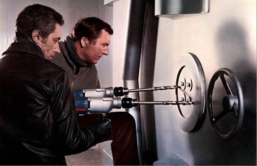 A film still from 'Pillaged' (1967). Two men drill into a large safe