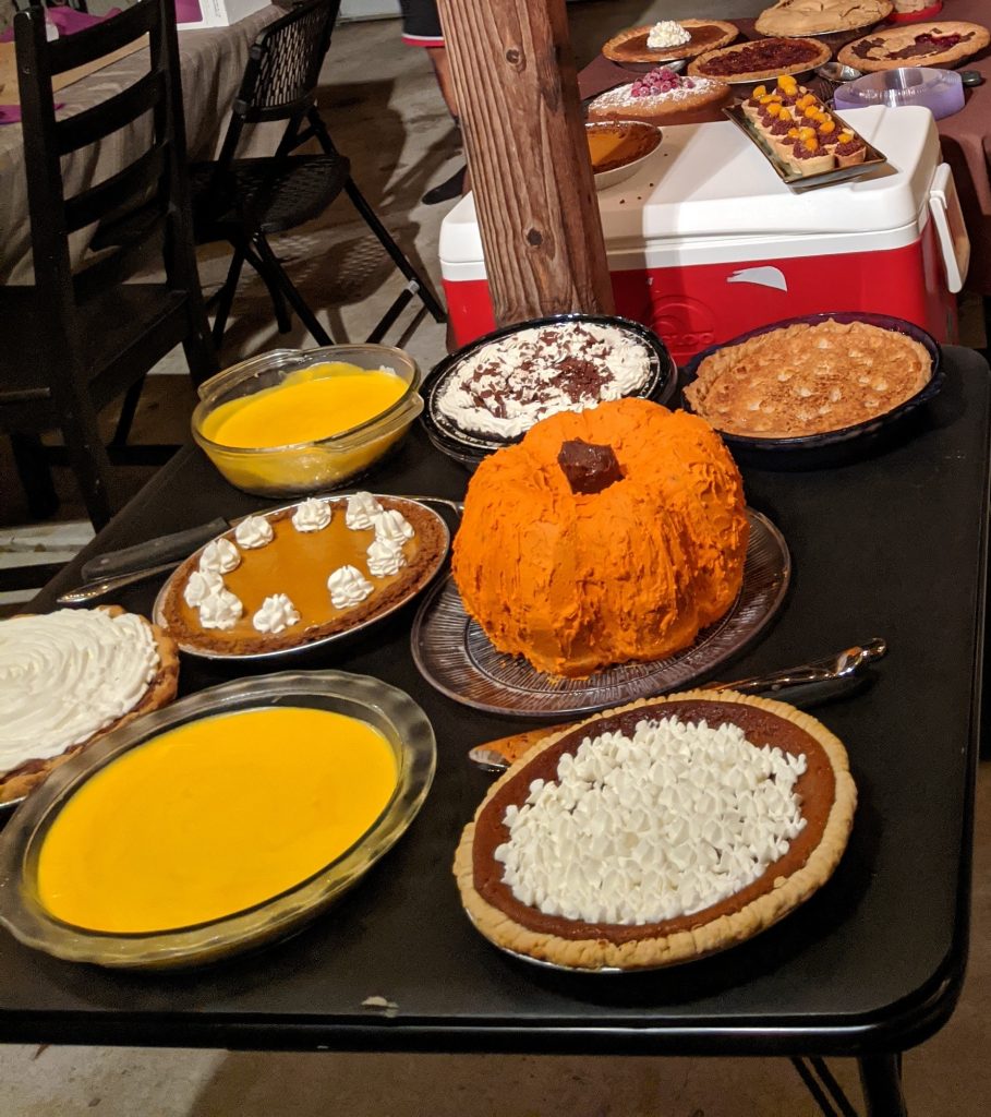 a Thanksgiving spread of many pies and a pumpkin shaped cake