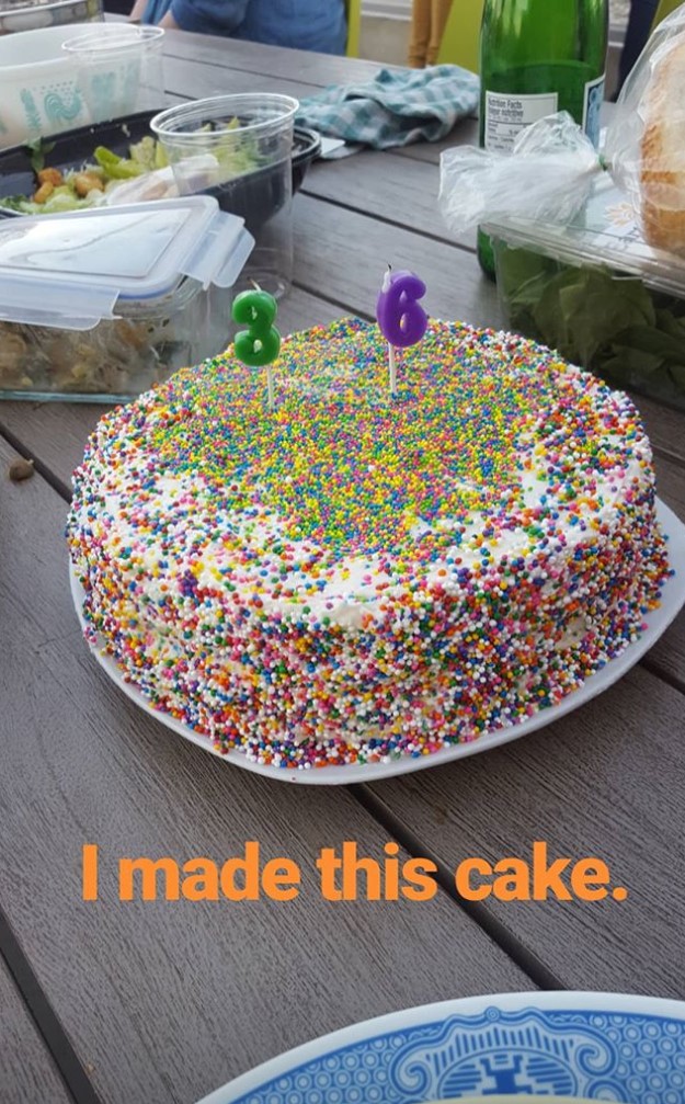 A cake with confetti sprinkles with a 3 candle and a 6 candle on top