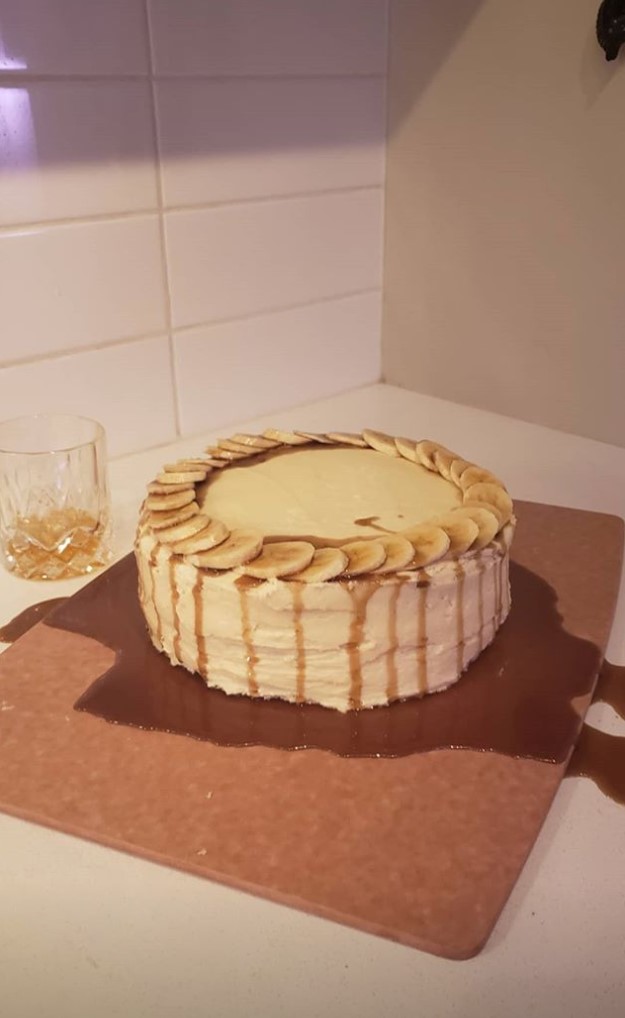 a round cake with banana slices around the perimeter with caramel drizzled along the side