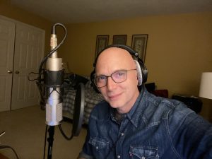 Michael Cerveris in front of a microphone with his headphones on