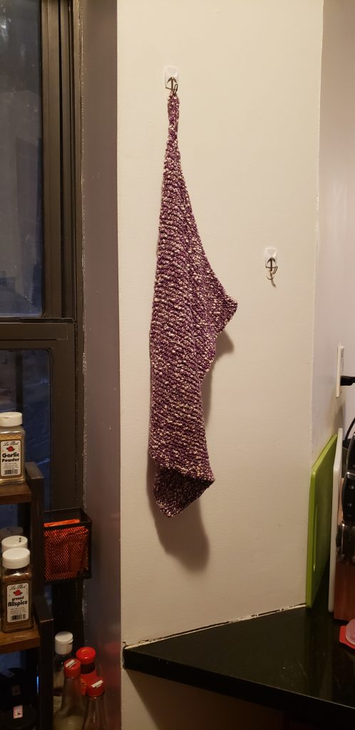 a red and white knitted nubbly cloth hanging from a wall hook