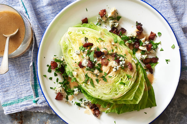 A wedge salad: One wedge of iceberg lettuce topped with dressing, bacon pieces, blue cheese crumbles, and parsley