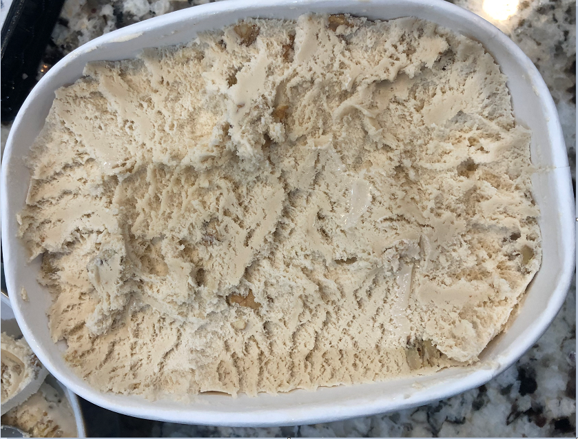 A container of maple walnut ice cream that has been scooped very evenly along the top layer.