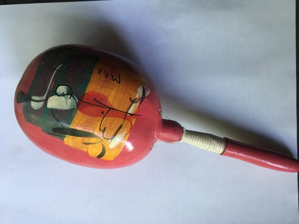 A red wooden, seemingly hand painted maraca. There is a green, orange and white design painted on it.