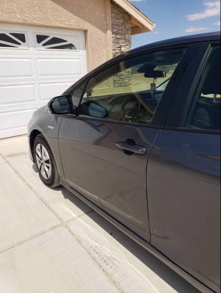 A closed gray Prius door with a dent in it