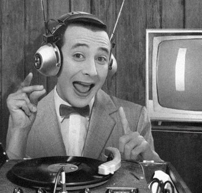 A black and white photo of Pee-wee with headphones on, spinning a record