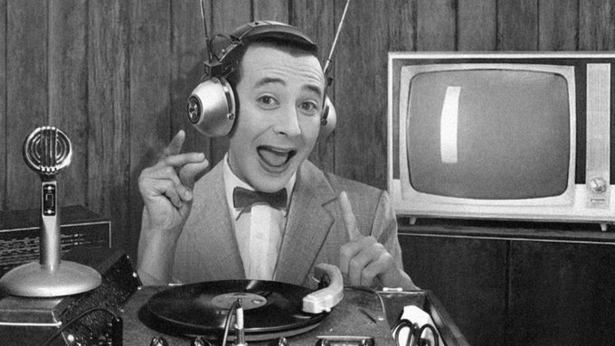 A black and white photo of Pee-wee with headphones on, spinning a record