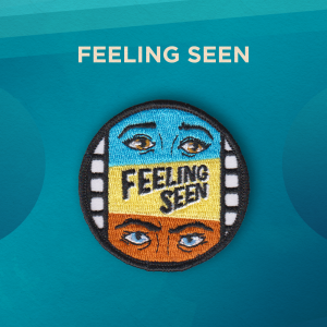 Feeling Seen. Within the edges of a roll of film are two pairs of eyes, on a blue and rust background. The words “Feeling Seen” are in the middle, on a yellow background.