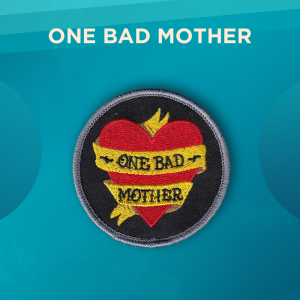 One Bad Mother. A yellow ribbon wrapped around a red heart on a black background. On the ribbon in black letters it reads “ONE BAD MOTHER”.