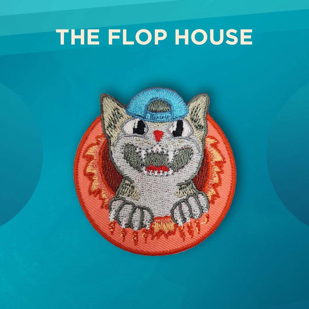 The Flop House. A gray cat wearing a backwards blue ball cap appears to have torn itself out of a circular orange patch. The cat is grinning widely and claw marks and tears appear on the orange background.
