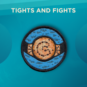 Tights and Fights. A round patch with a blue background and a cookie-colored wrestling belt with chocolate chips outlining the letter C. The blue background has furry details.