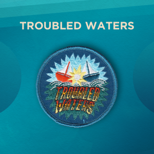 Troubled Waters. A red and a blue sailboat crash into each other with a yellow explosion. Below, the words “Troubled Waters” in red, yellow, and white block letters. The background is blue.