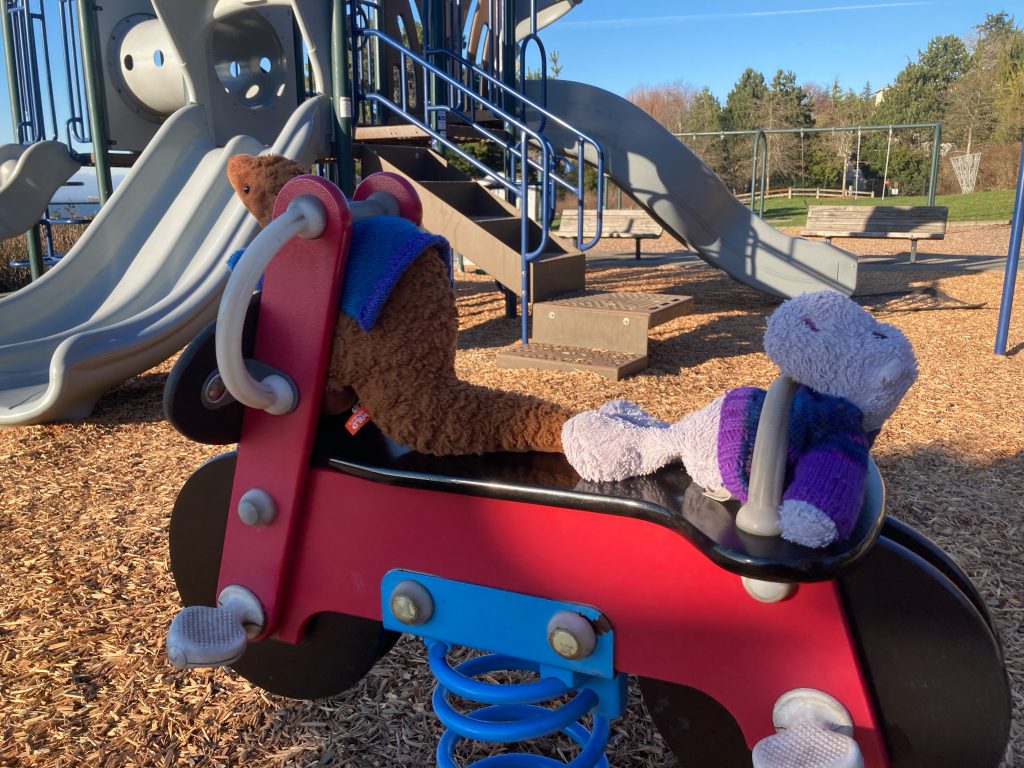 Two stuffed animals on playground equipment