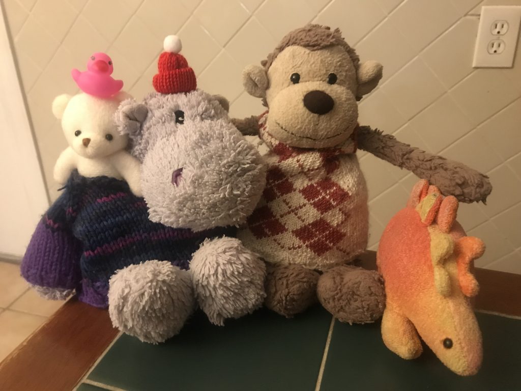 A stuffed bear, hippo, monkey, and stegosaurus