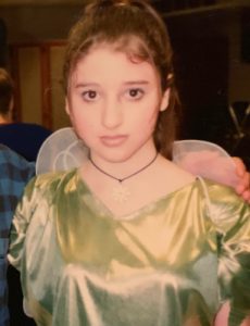Kerri Doherty as a teen. She's in what appears to be a tinkerbell costume with a green dress and fairy wings. Her expression says she's not thrilled about the outfit. 