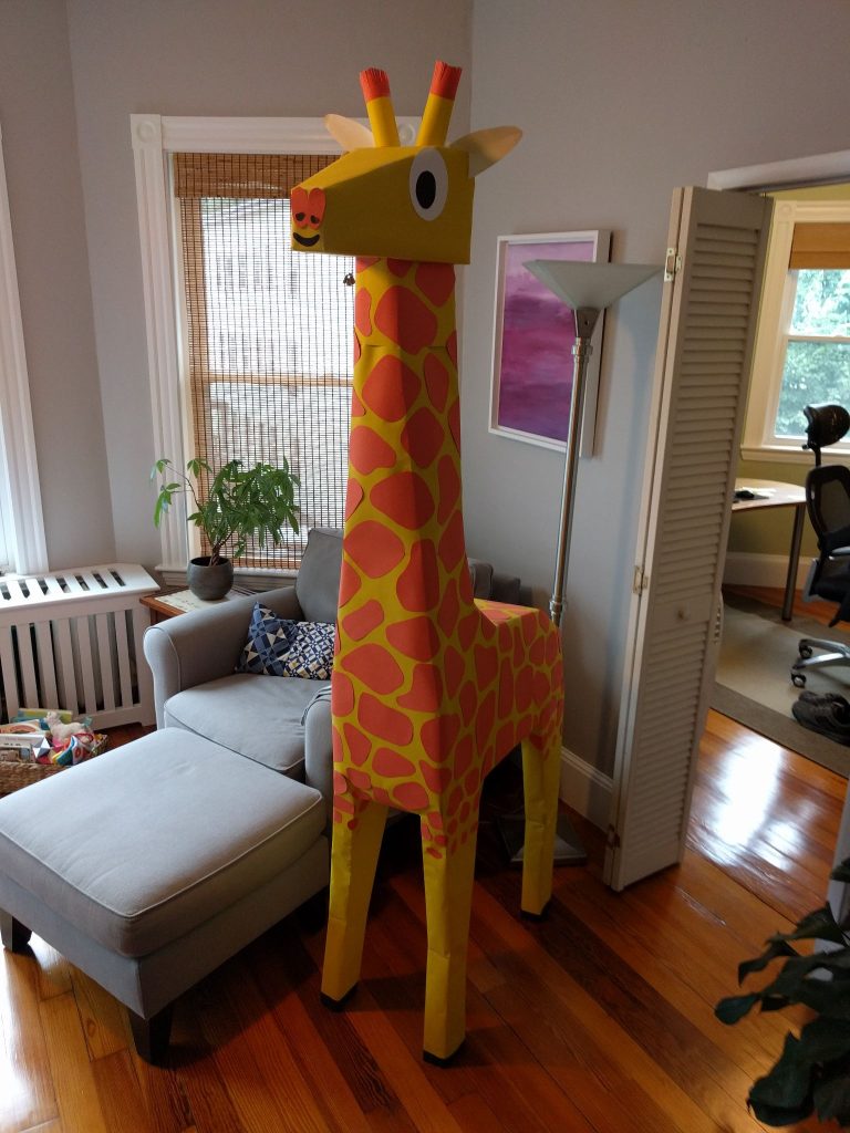 An 8 foot tall paper sculpted giraffe in a living room