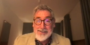 John Landis in a zoom window smiling at the camera. He's wearing glasses.