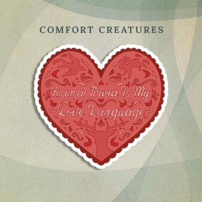 Comfort Creatures: A light red heart with dark red scalloping and animal designs drawn on it as if they’ve been embroidered into fabric. “Animal Trivia Is My Love Language” is written in the center in the same embroidered style.