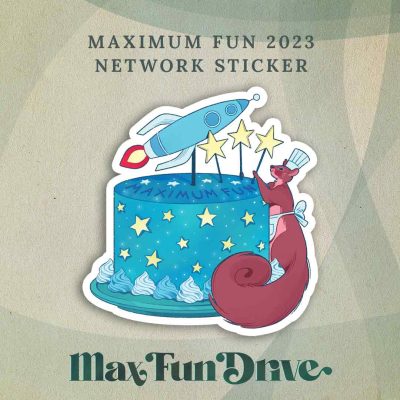 Maximum Fun 2023 Network Sticker: Nutsy, a squirrel and Max Fun’s mascot, is wearing a chef hat and apron and decorating a cake. The cake is blue, says “Maximum Fun” on the top, and has the Maximum Fun rocket logo plus three stars sticking out on toothpicks along the top.