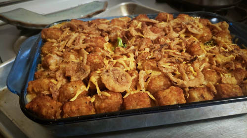 A casserole-like dish full of broccoli, cheddar cheese, tater tots.