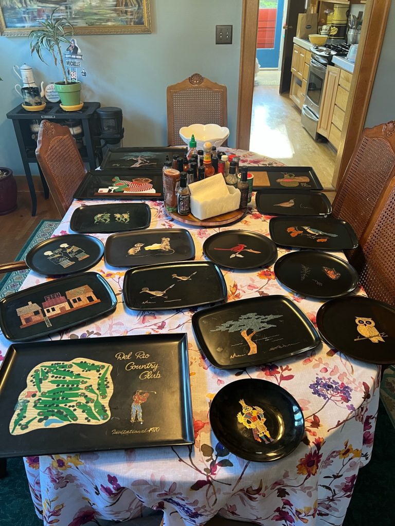 a dining room table full of many black trays with inlaid designs