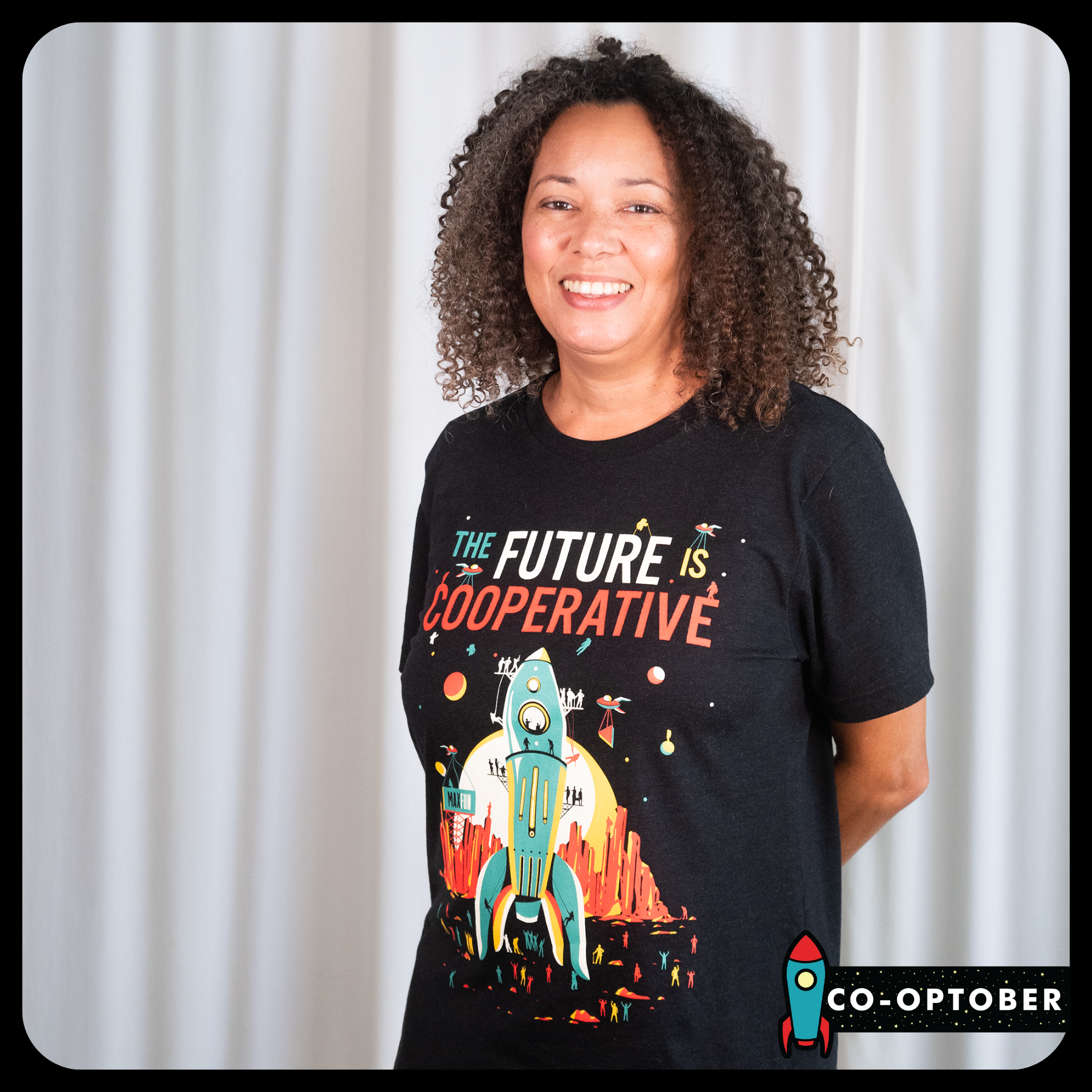 Laura Swisher wearing a black T-shirt that says The Future is Cooperative and above an illustration of a rocket being built.