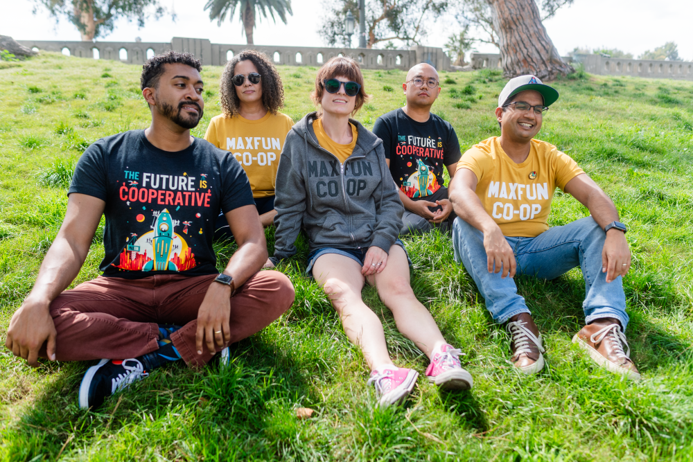 MaxFun worker-owners showing off the new Co-Optober merch outside in a park