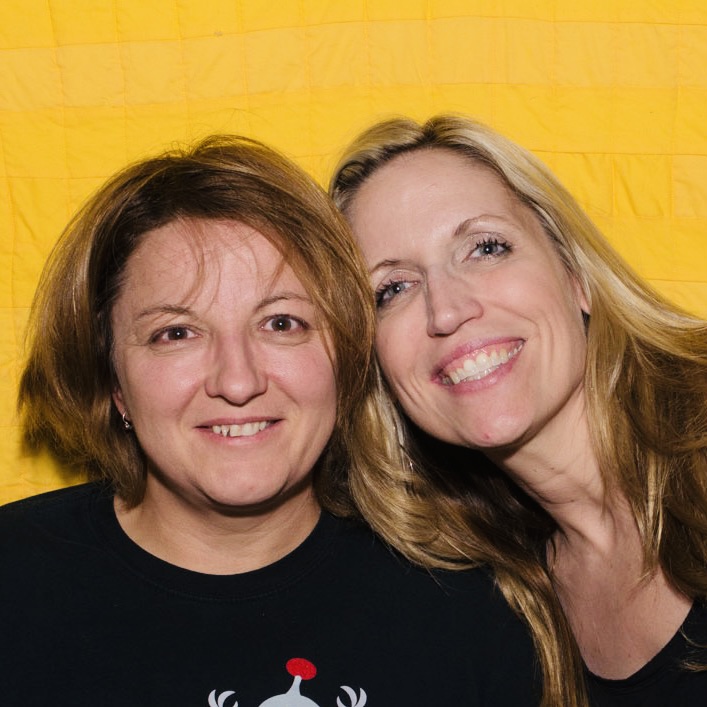 Jackie Kashian and Laurie Kilmartin in front of a yellow background