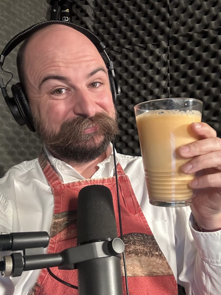 Bailiff Jesse in the studio holding a class of a creamy orange looking drink