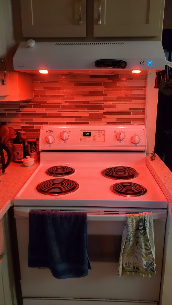 A stove with red lights shining from the hood