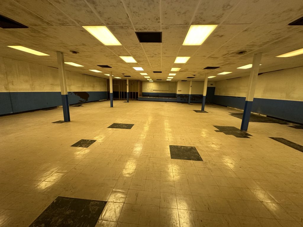 an empty, dimly florescent lit room with a yellow tinge, and tiles.