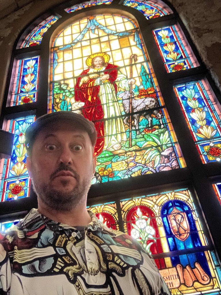 A man in front of a large church stained glass window
