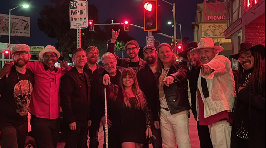 a group photo with 12 people in it, taken at night with a reddish light washing over them from a nearby stoplight