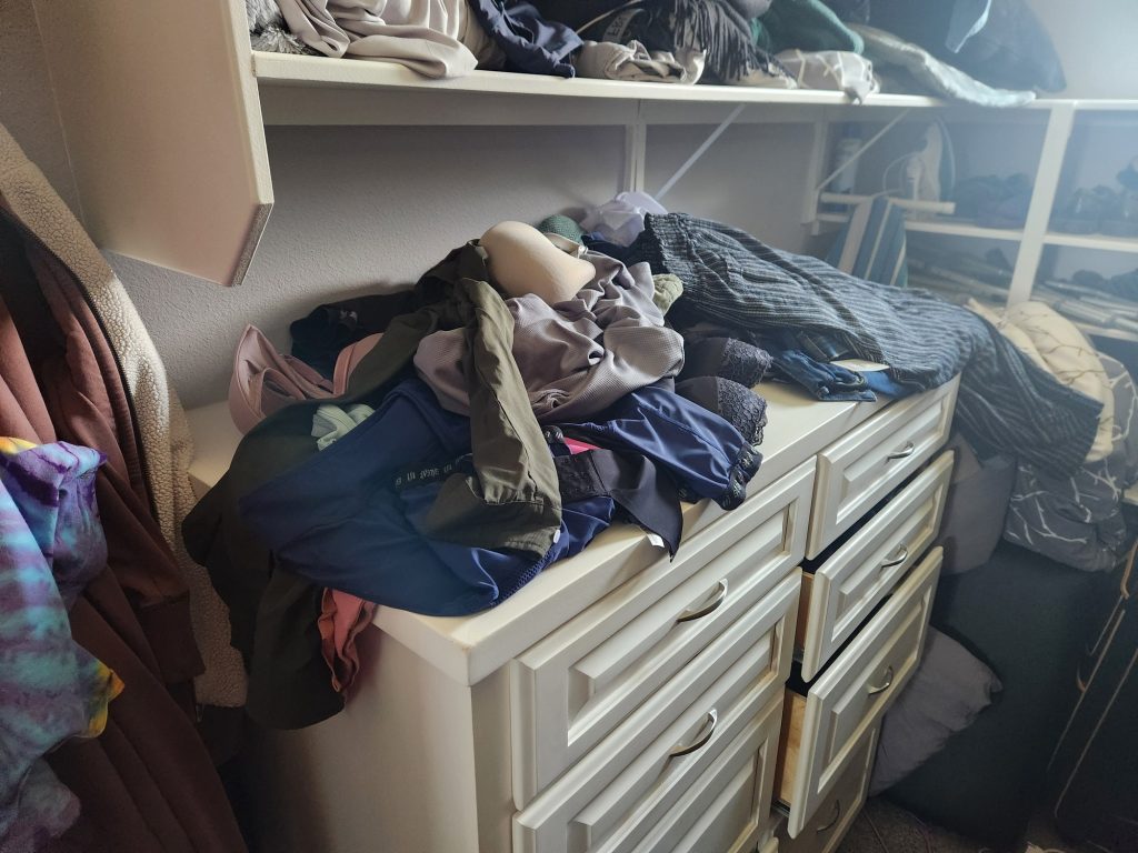 A pile of clothes on top of a dresser.