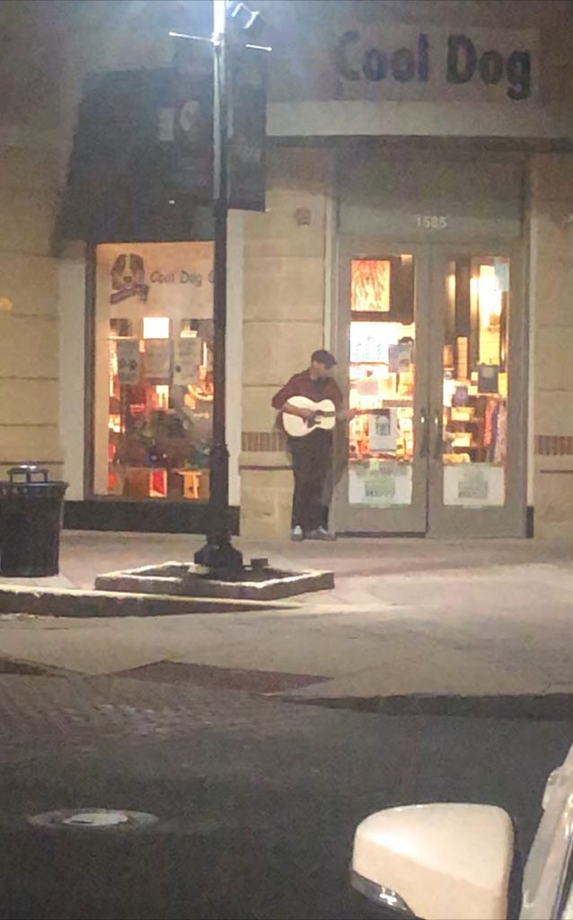 A man playing a guitar outside a store