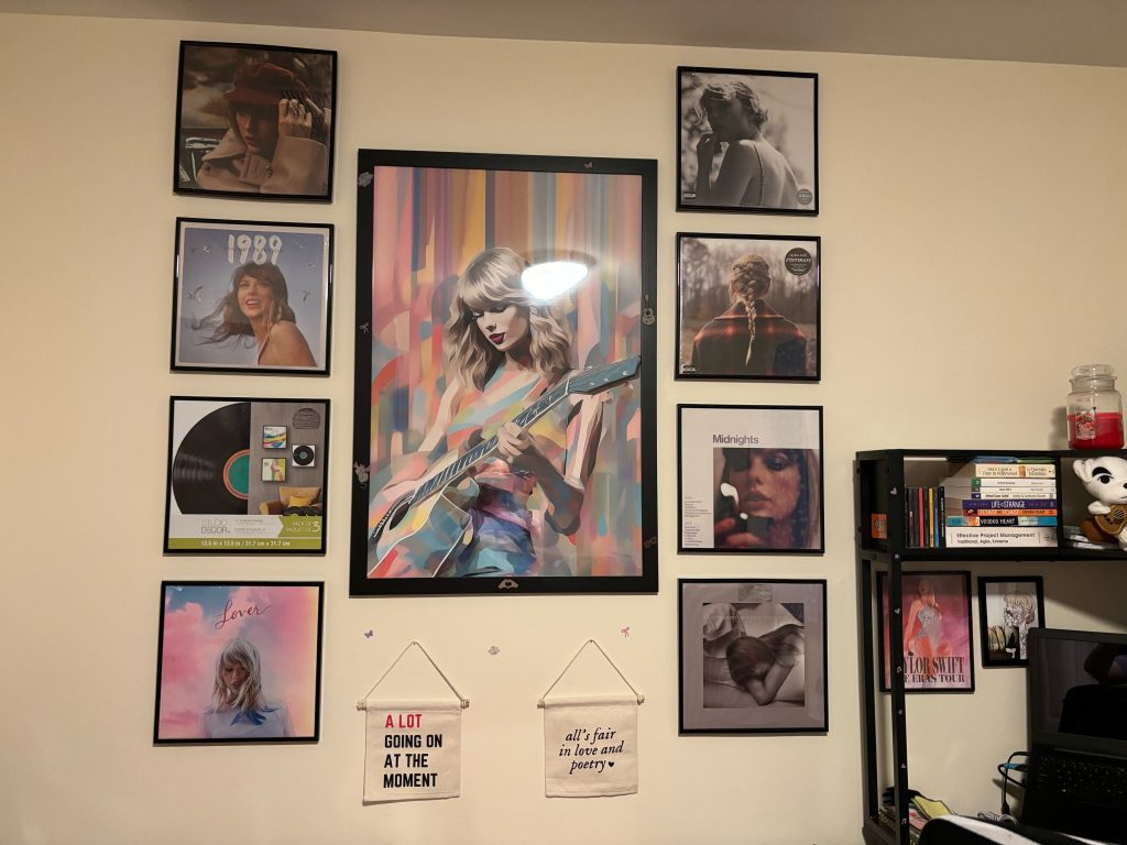 A gallery wall with a painting of Taylor Swift in the center surrounded by Taylor Swift album cover art