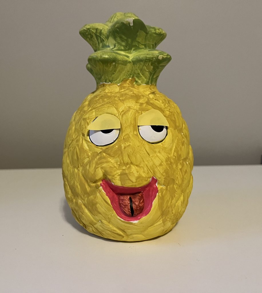 The same pineapple, but with yellow sticky notes cut into eyelid shapes covering half of the eyes