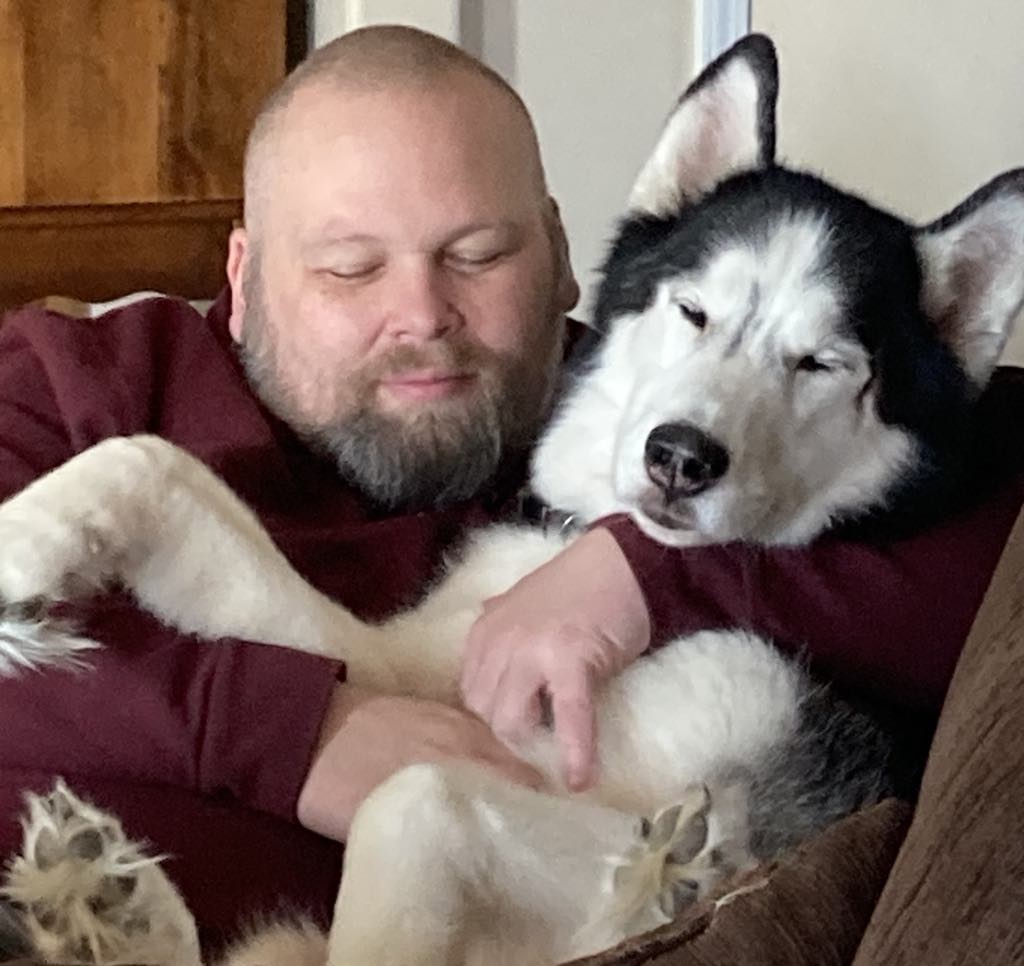 a person and a husky dog snuggled together both with their eyes closed