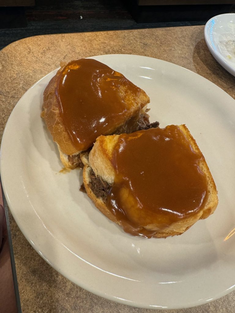 A sandwich cut in half on a plate, with gravy poured over the top