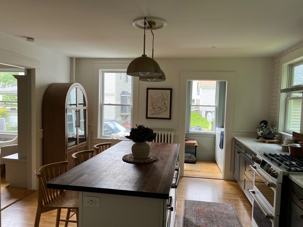 A kitchen with a large island in the middle and windows that have a view of another house