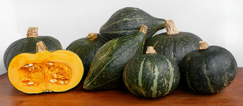 a stock image of green Taiwanese pumpkins, one of which is cut to reveal and orange interior