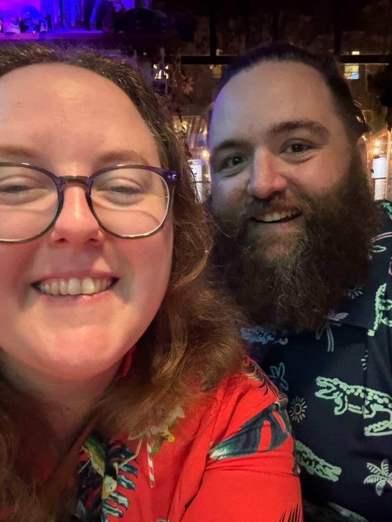 two people, one with glasses, the other with a beard, smiling for a selfie