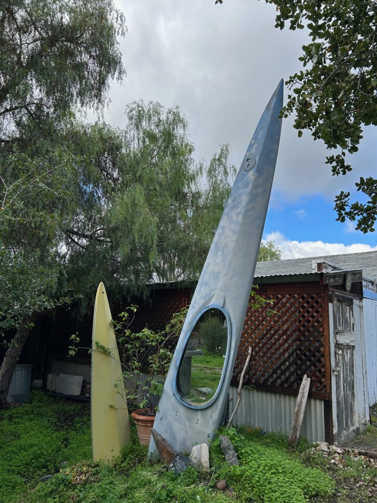 Two kayaks sticking up vertically out of the ground in a backyard.