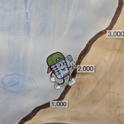 a hand drawn mountainside with measurements at 1,000, 2,000 and 3,000 being scaled by Mikey the microphone, our MFD mascot